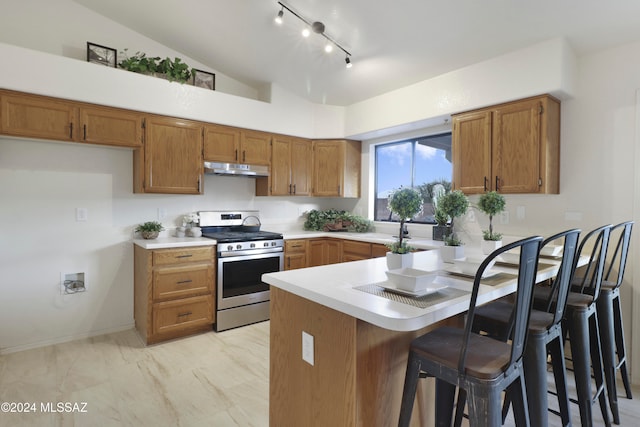 kitchen with kitchen peninsula, a breakfast bar, vaulted ceiling, sink, and stainless steel stove