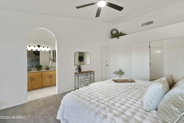 bedroom featuring ensuite bath, ceiling fan, sink, high vaulted ceiling, and light colored carpet