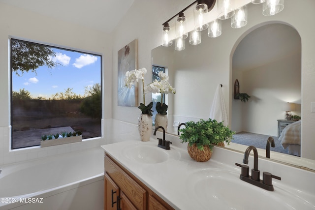 bathroom featuring a bathing tub, vanity, and vaulted ceiling