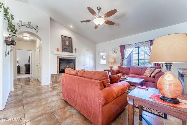 tiled living room with a tile fireplace, ceiling fan, and vaulted ceiling