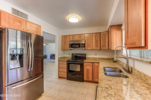 kitchen with light tile patterned flooring, appliances with stainless steel finishes, light stone counters, and sink