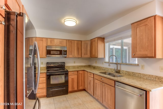 kitchen featuring light stone counters, sink, light tile patterned flooring, and stainless steel appliances