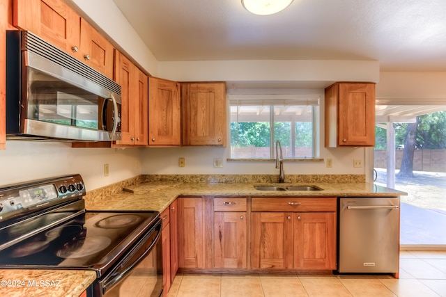 kitchen featuring light stone countertops, sink, light tile patterned flooring, and black range with electric cooktop