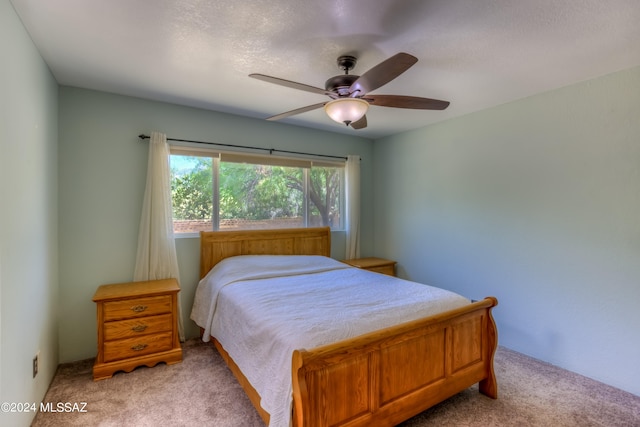 carpeted bedroom with ceiling fan and a textured ceiling