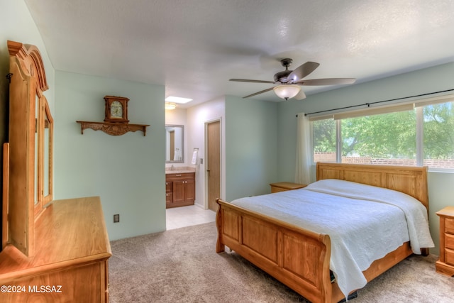 carpeted bedroom featuring ensuite bath, ceiling fan, and a textured ceiling