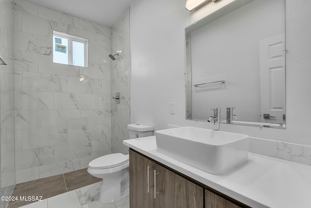 bathroom featuring tiled shower, vanity, and toilet