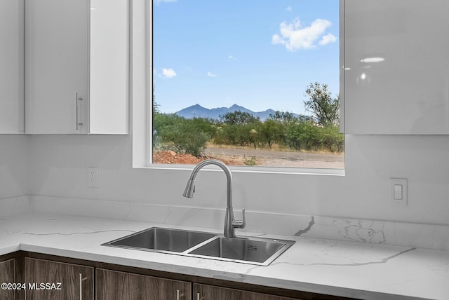 kitchen featuring a mountain view, dark brown cabinetry, sink, and a wealth of natural light