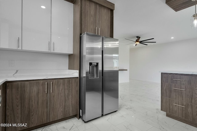 kitchen featuring white cabinetry, ceiling fan, light stone countertops, stainless steel refrigerator with ice dispenser, and pendant lighting