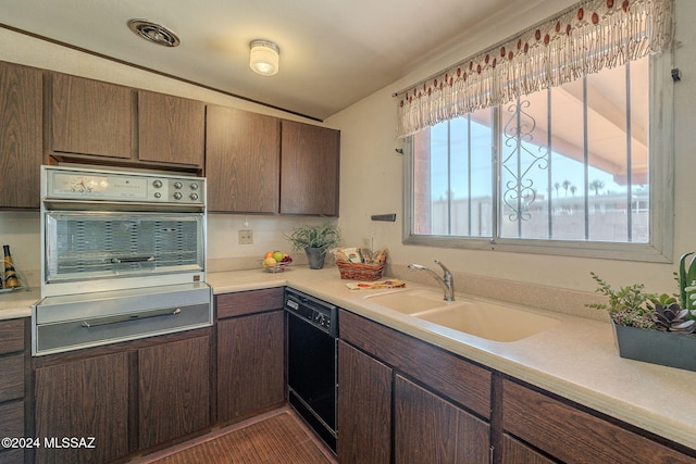 kitchen featuring black dishwasher, light countertops, a sink, and stainless steel oven