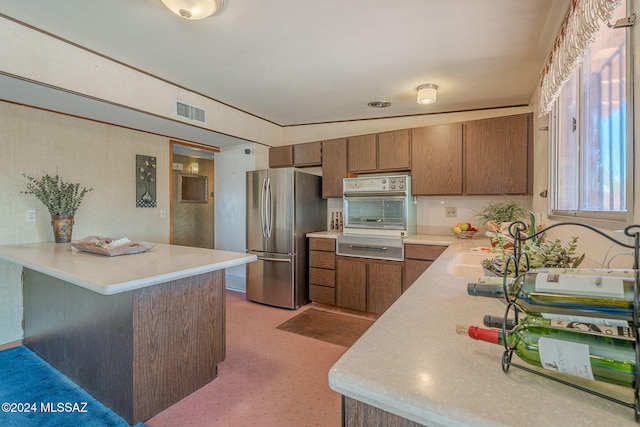 kitchen with stainless steel refrigerator, kitchen peninsula, sink, and oven