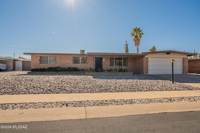 ranch-style house with driveway, a garage, and brick siding