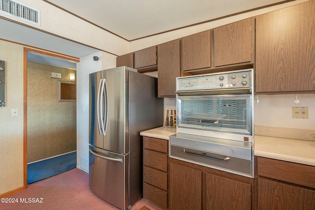 kitchen featuring brown cabinetry, visible vents, appliances with stainless steel finishes, and light countertops