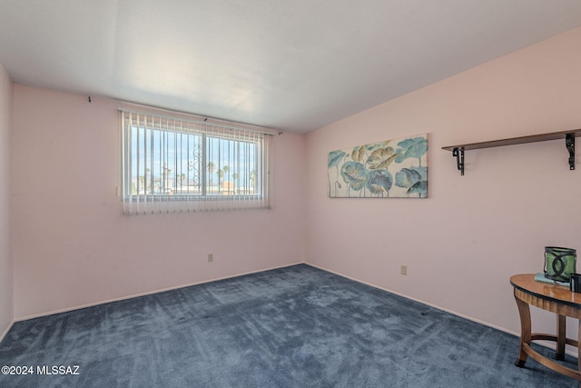 unfurnished room with lofted ceiling and dark carpet