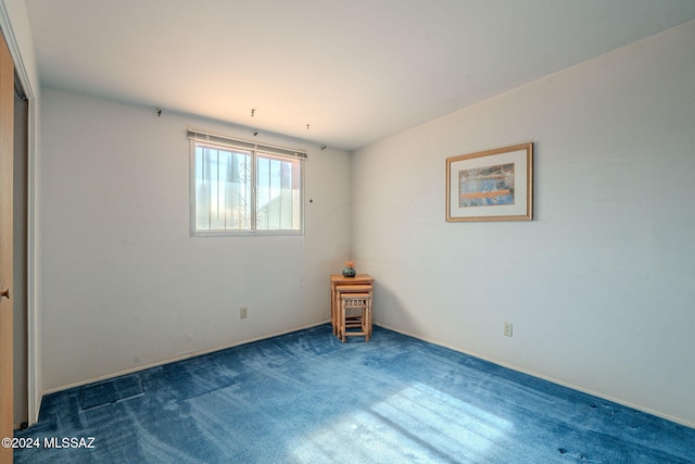 spare room with dark carpet