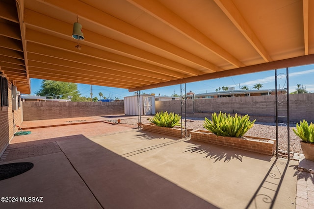 view of patio featuring an outbuilding, a storage unit, and a fenced backyard