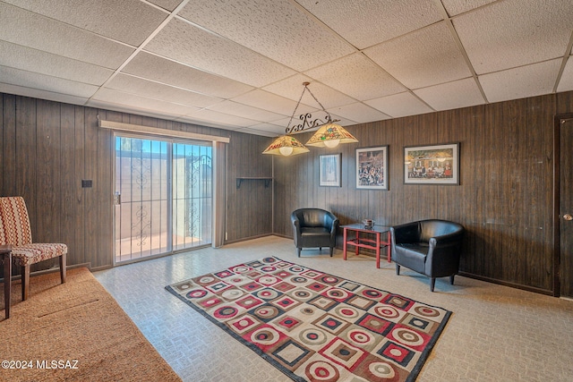 sitting room featuring a paneled ceiling and wood walls