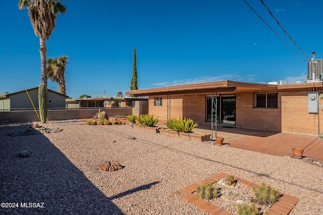 back of house featuring brick siding, a patio area, and fence