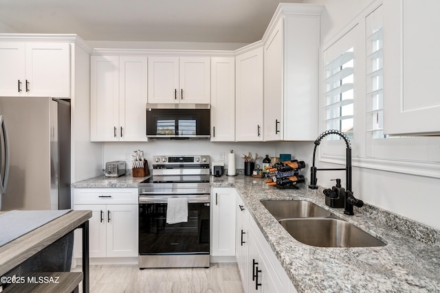 kitchen featuring appliances with stainless steel finishes, a sink, and white cabinets