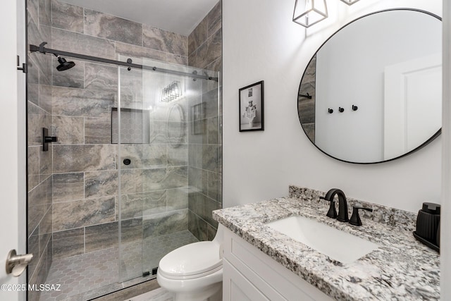 bathroom featuring vanity, a shower with door, and toilet