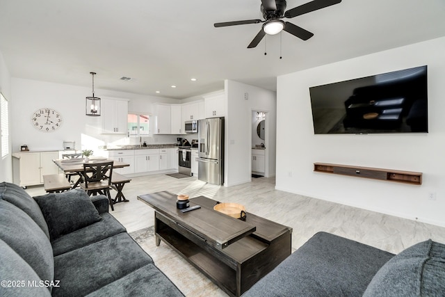 living area with a ceiling fan and recessed lighting