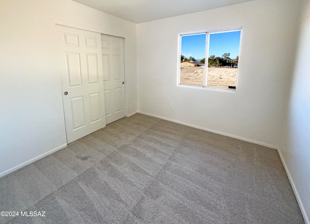 unfurnished bedroom featuring light colored carpet and a closet