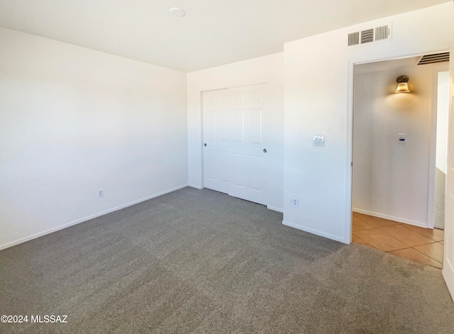 unfurnished bedroom featuring dark carpet and a closet