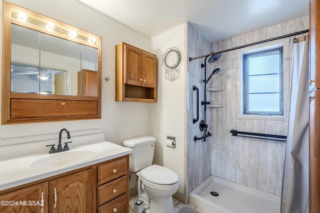 bathroom with tile patterned floors, vanity, toilet, and a tile shower