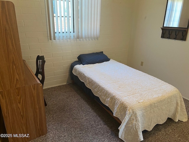 bedroom with dark colored carpet and brick wall