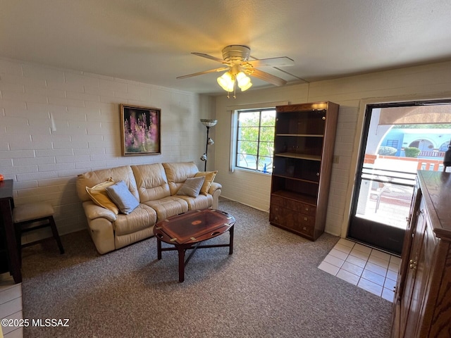 living room featuring ceiling fan, light carpet, and brick wall