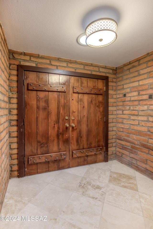 interior space featuring brick wall and a textured ceiling