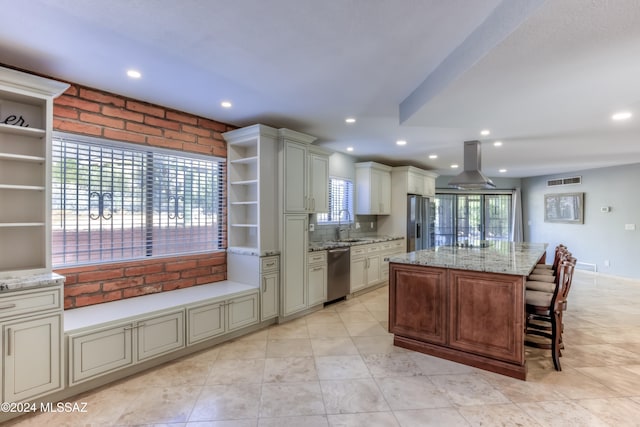 kitchen featuring light stone counters, appliances with stainless steel finishes, island range hood, and a kitchen island