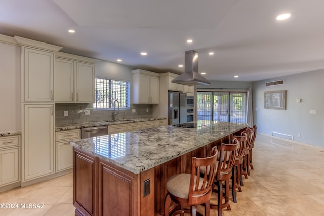 kitchen featuring appliances with stainless steel finishes, island exhaust hood, sink, a large island, and light stone counters