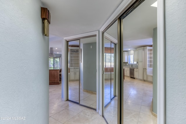 hallway featuring sink, plenty of natural light, and light tile patterned flooring