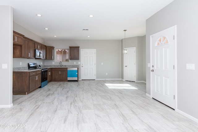 kitchen with pendant lighting, sink, stainless steel appliances, light stone counters, and dark brown cabinetry