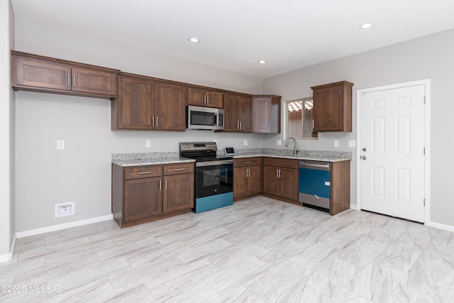 kitchen with light stone countertops, appliances with stainless steel finishes, and sink