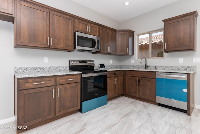 kitchen featuring dark brown cabinetry, stainless steel appliances, light stone countertops, and sink