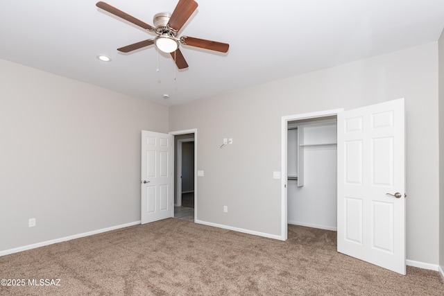 unfurnished bedroom featuring a walk in closet, carpet floors, ceiling fan, and a closet