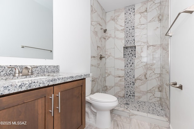 bathroom with vanity, toilet, and a tile shower