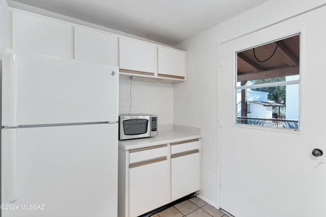 kitchen featuring white fridge, white cabinetry, and light tile patterned floors