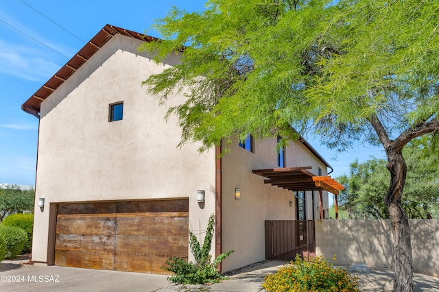 view of front of property featuring fence, an attached garage, and stucco siding