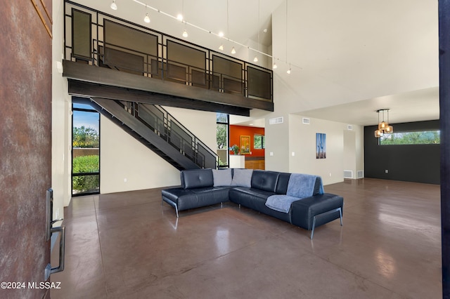 unfurnished living room featuring visible vents, concrete floors, a high ceiling, and stairs