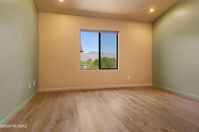 spare room featuring a mountain view and light wood-type flooring