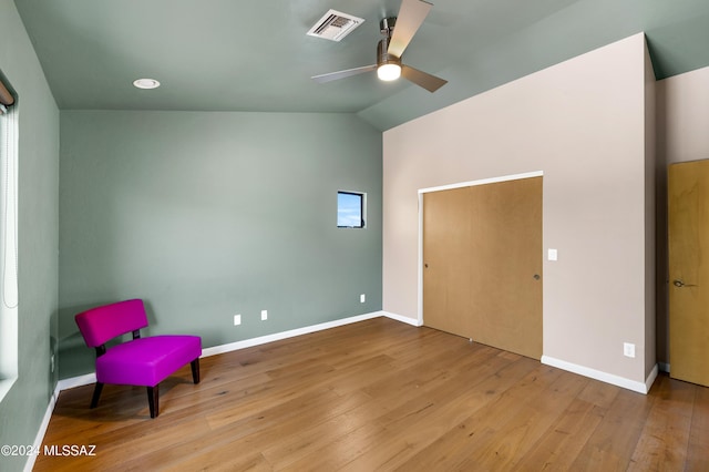 unfurnished room with vaulted ceiling, wood finished floors, visible vents, and baseboards