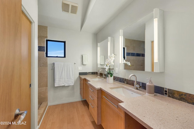 bathroom featuring hardwood / wood-style floors, vanity, and a tile shower