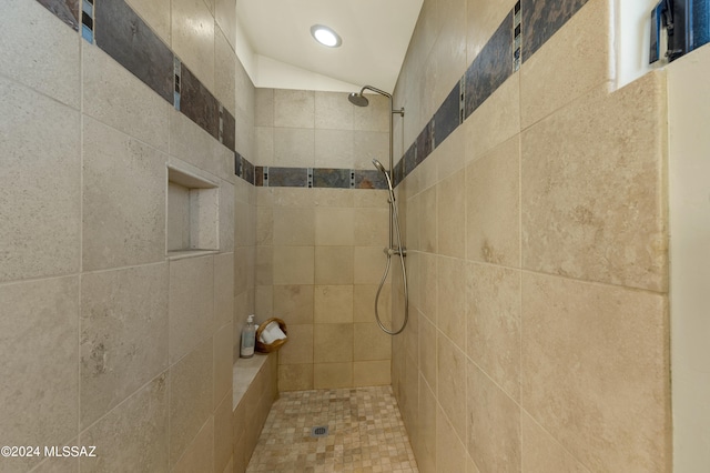 bathroom featuring a tile shower and lofted ceiling