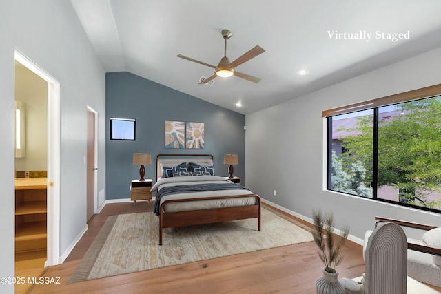 bedroom with lofted ceiling, baseboards, wood finished floors, and ensuite bathroom