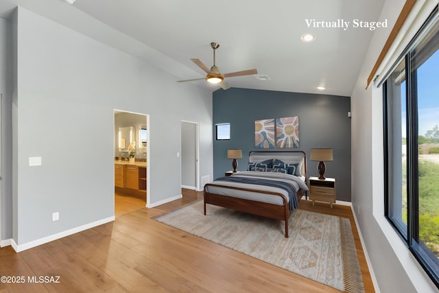 bedroom featuring visible vents, baseboards, lofted ceiling, ensuite bathroom, and light wood-type flooring