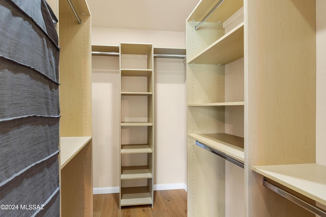 walk in closet with wood finished floors