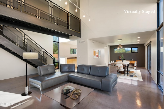 living room featuring stairs, a high ceiling, visible vents, and finished concrete floors