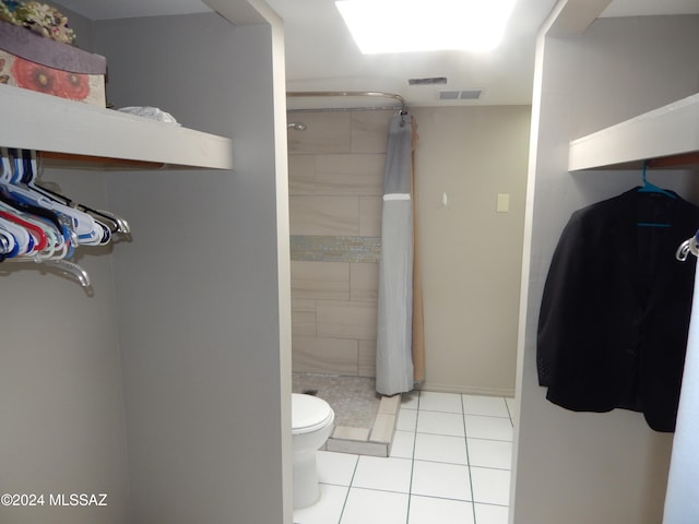 bathroom featuring tile patterned flooring, toilet, and curtained shower